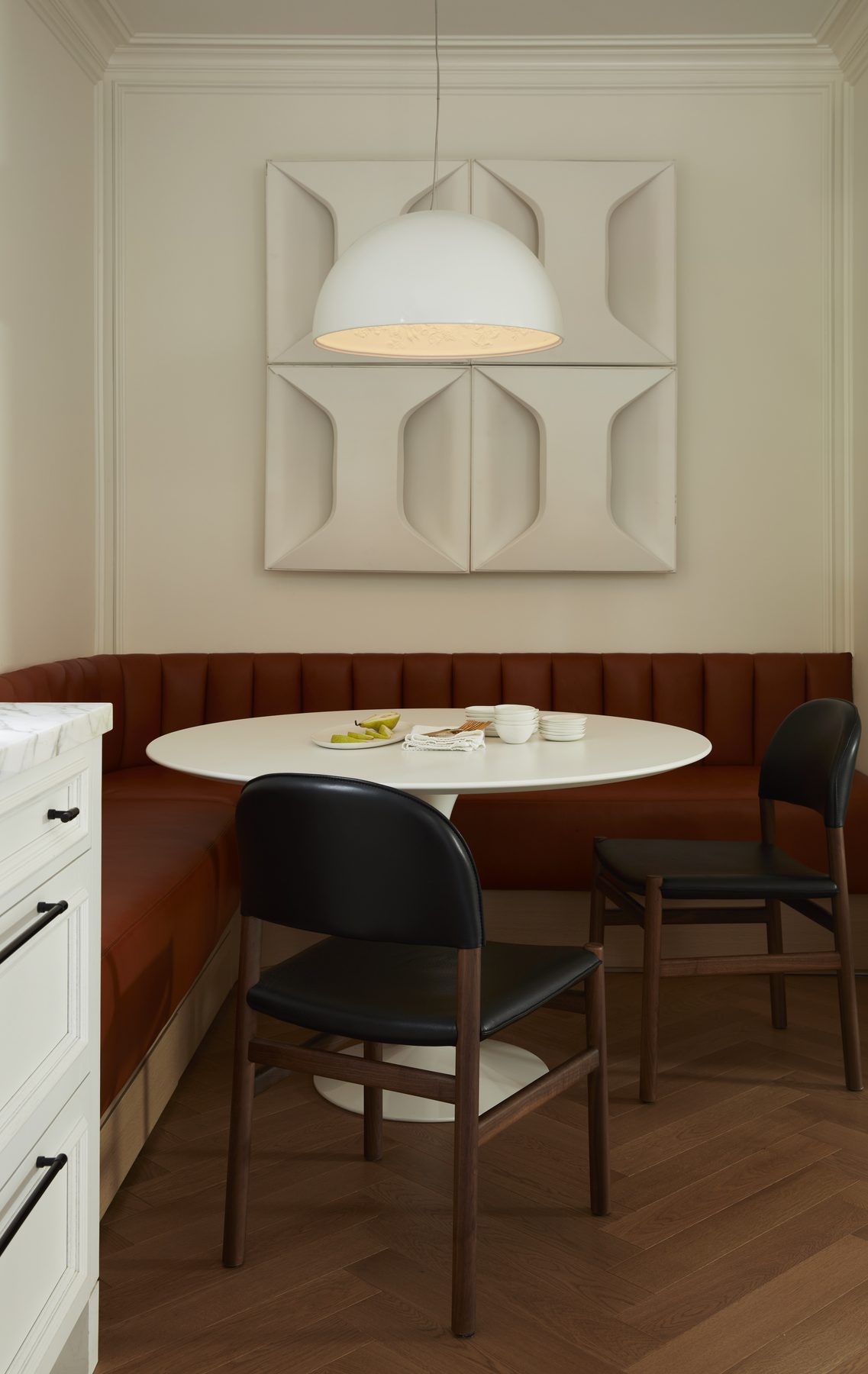 Midtown House kitchen banquette with cognac leather seating, white tulip table and sculptural geometric wall panel