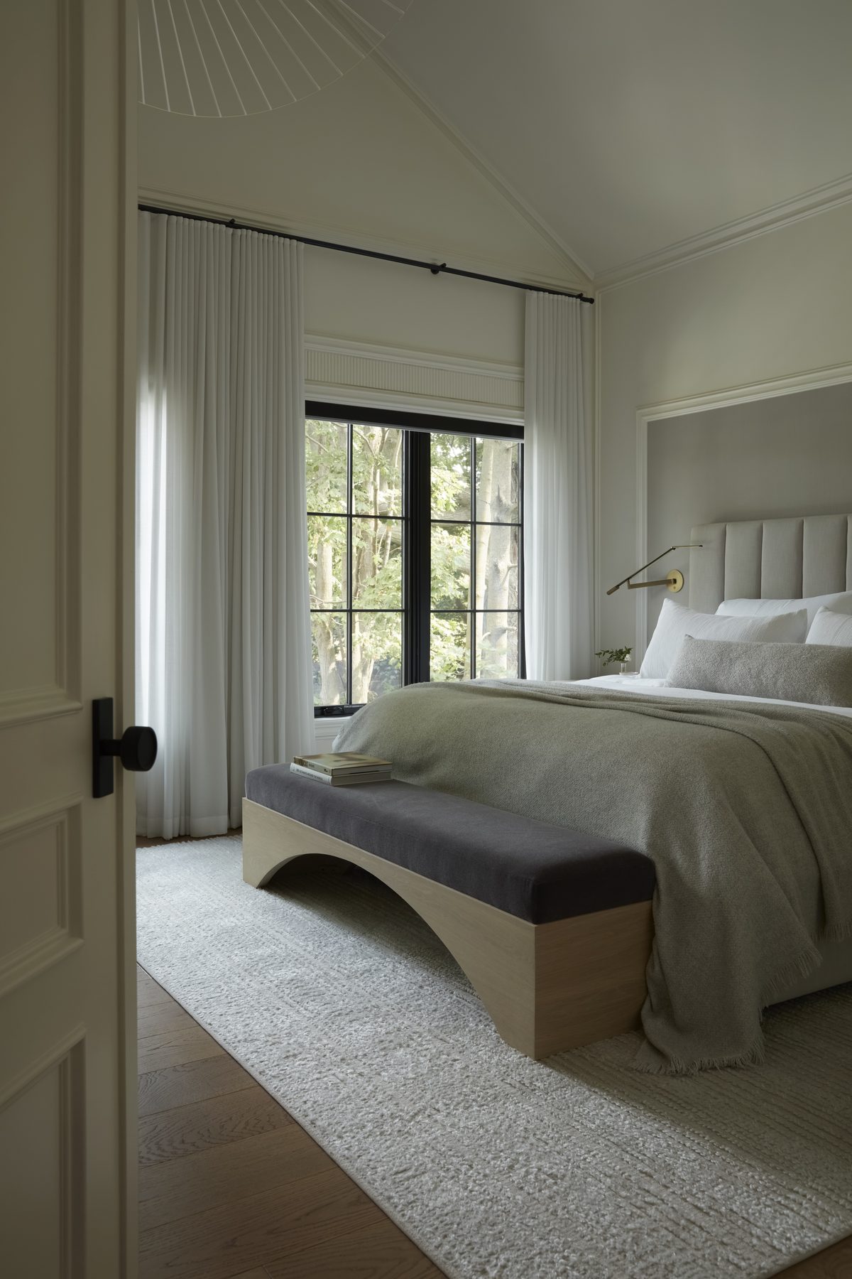 Midtown House primary bedroom with channeled headboard, sage linen bedding and arched bench