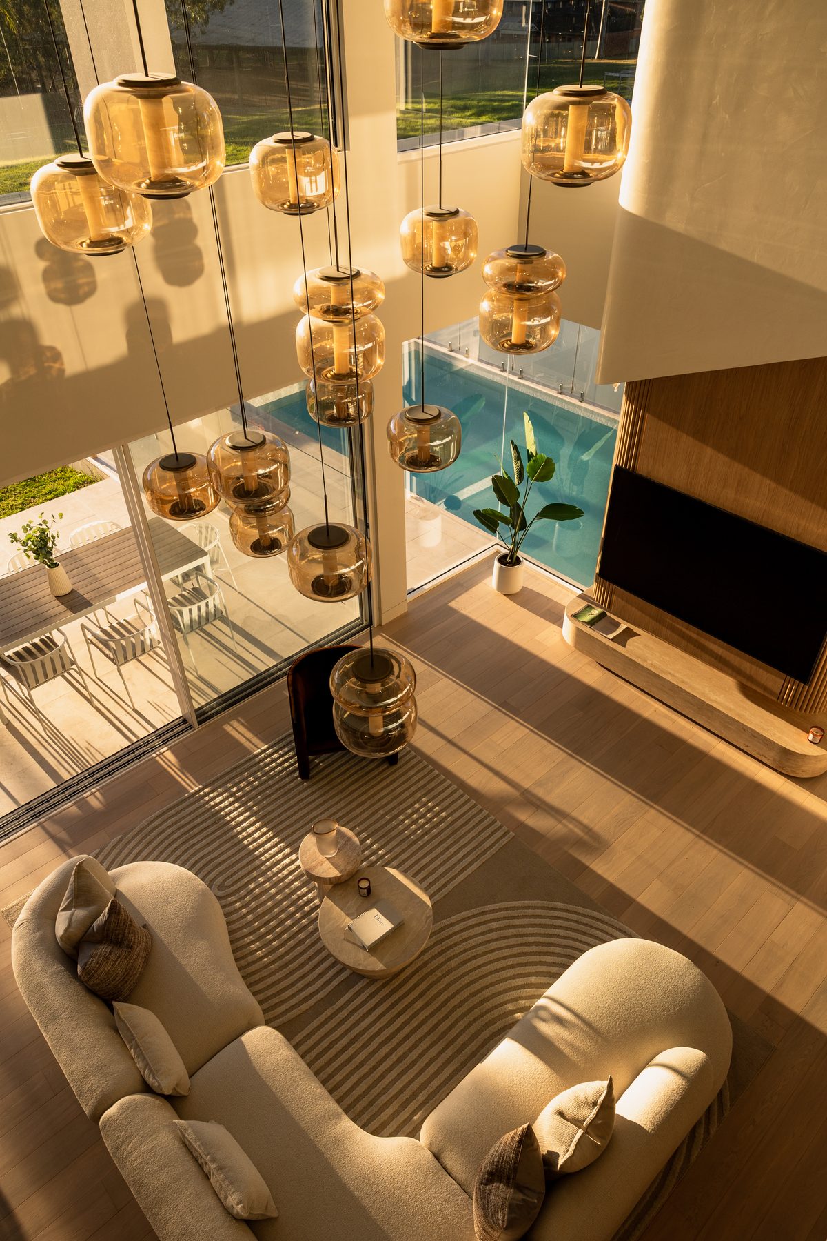 Overhead view of double-height living room with cascading amber glass pendants, Girraween House