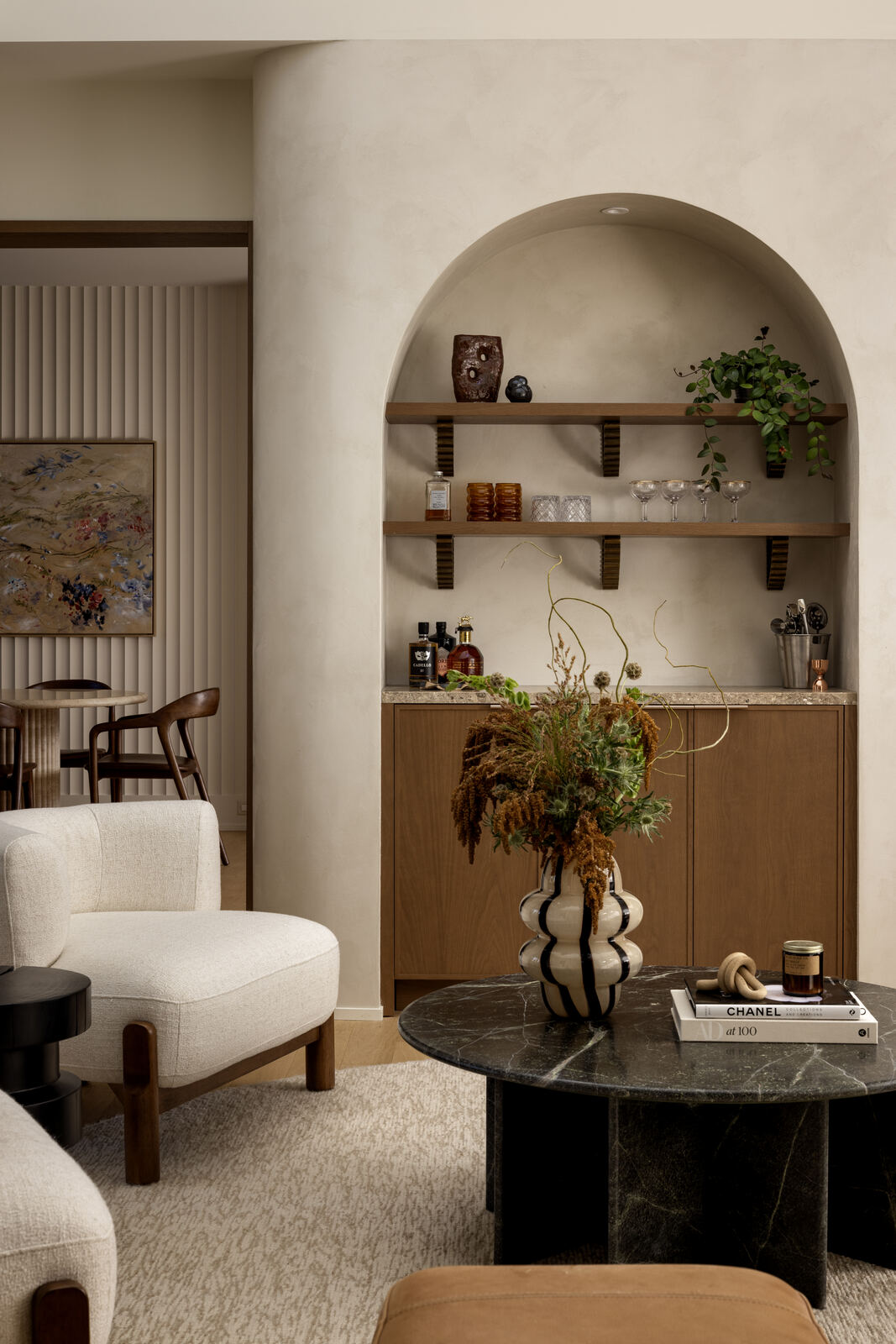 Arched niche with oak shelving and bar cabinet beside a boucle lounge chair, Madison Residence