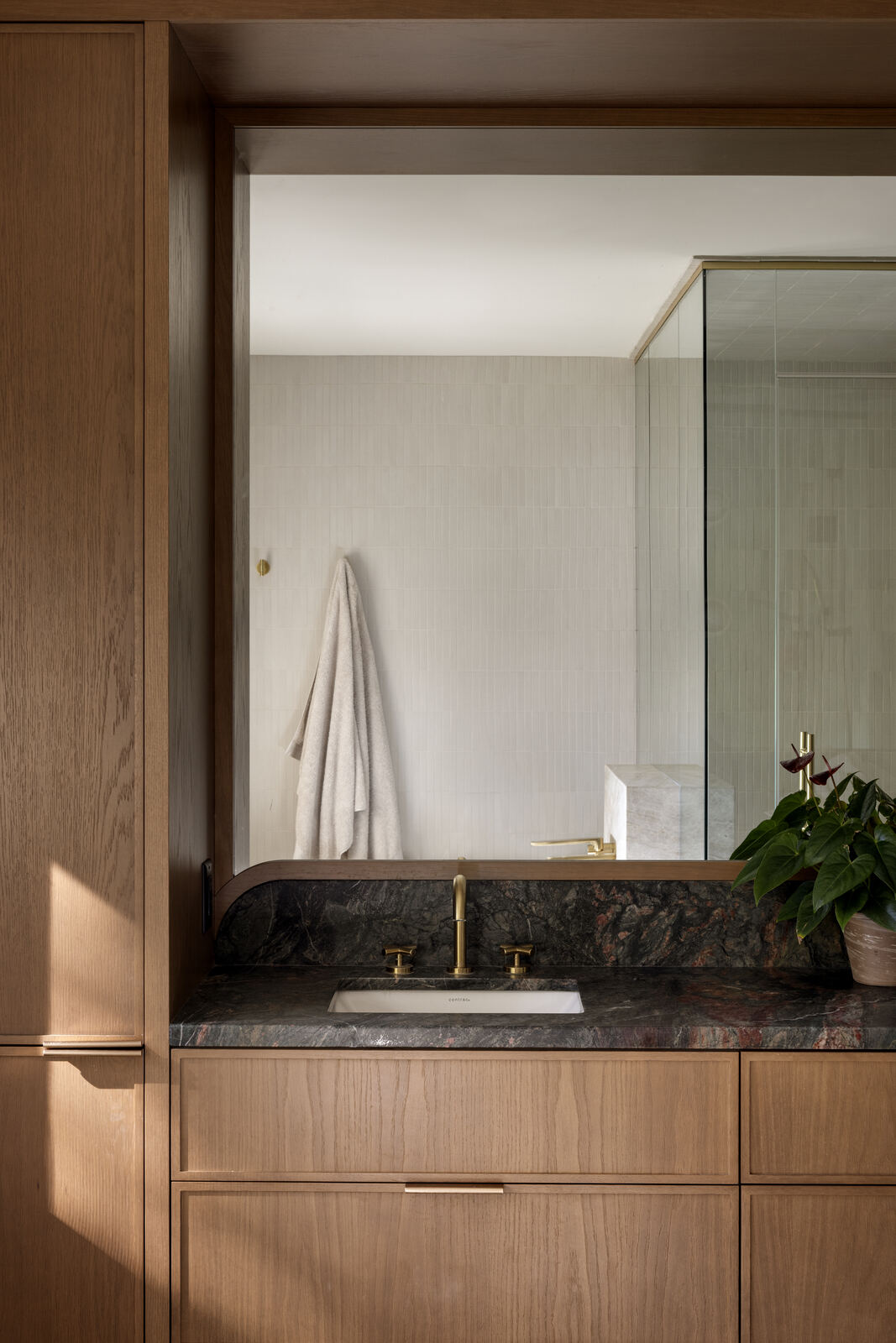 Bathroom vanity in oak with green stone top beside a glass shower, Madison Residence
