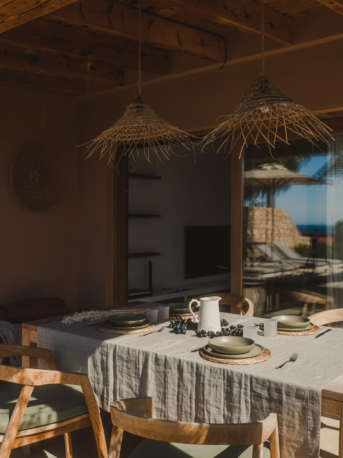 Dining table set beneath woven rattan pendants, Casa M