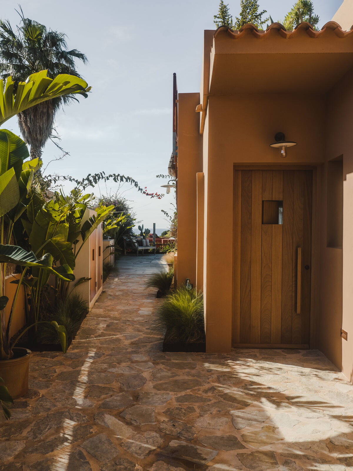 Terracotta rendered exterior with stone path and palms, Casa M