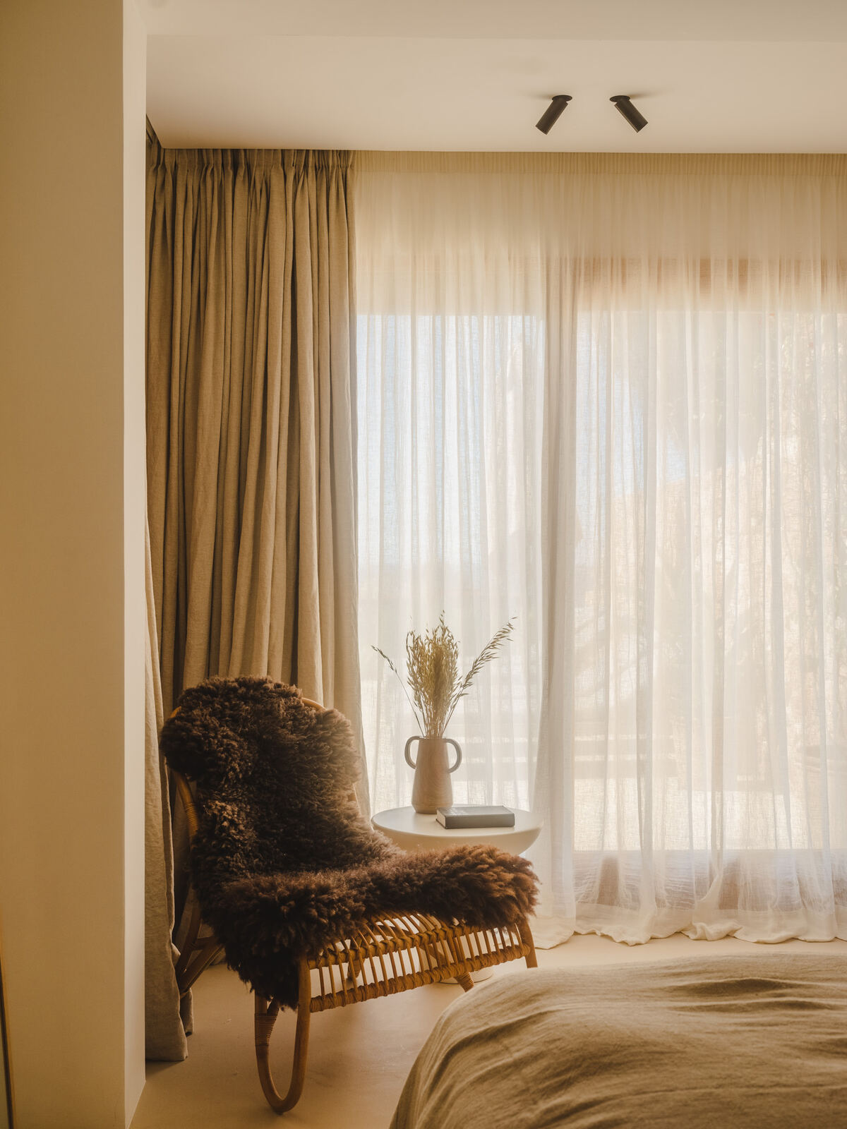 Bedroom corner with sheepskin chair and sheer curtains, Casa M