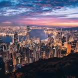 City skyline at dusk with illuminated skyscrapers and a colorful sky.
