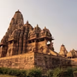 Ancient stone temple with detailed carvings under a clear sky during sunset.