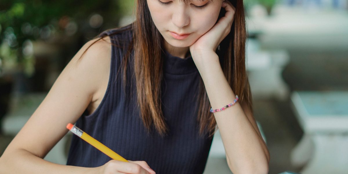 Photo of a person diligently studying, with notes and learning materials, in a relaxed coffee shop environment.