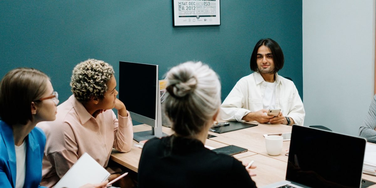 A team of professionals engaged in a thoughtful discussion about ethical considerations in AI development, highlighting a focus on human well-being.