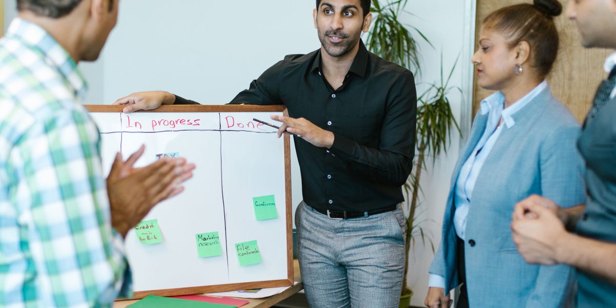 A diverse team of professionals engaged in an ethical discussion around a whiteboard in an office setting.