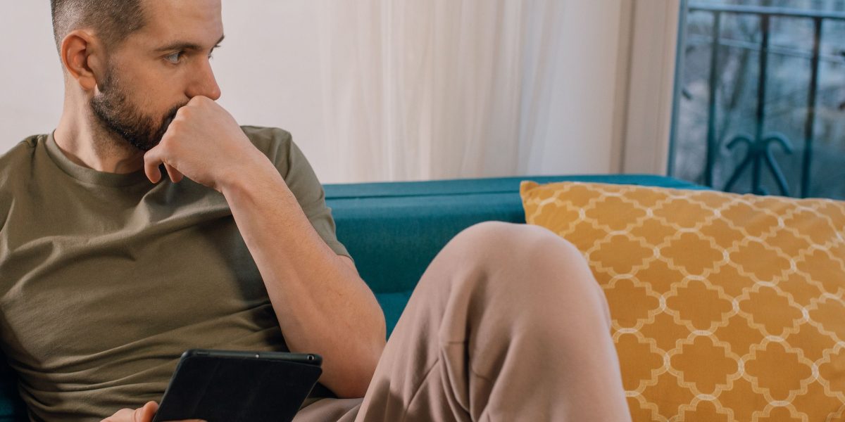 A person looking thoughtful and concerned while reviewing content on a tablet, reflecting the erosion of trust in digital information.