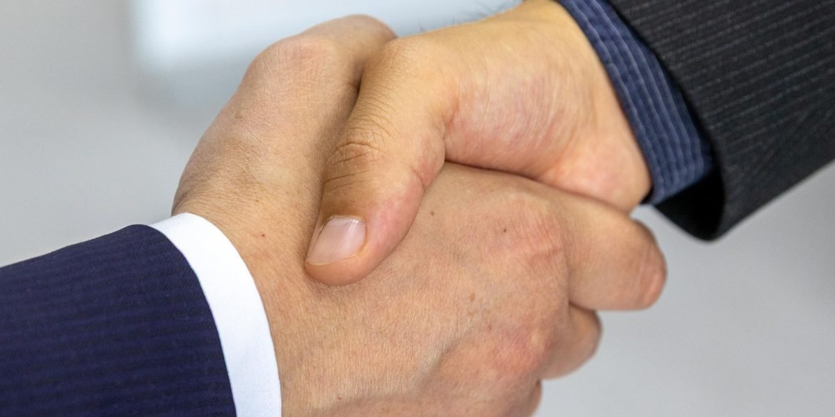 Two professionals shaking hands, symbolizing agreement and trust in a professional setting.