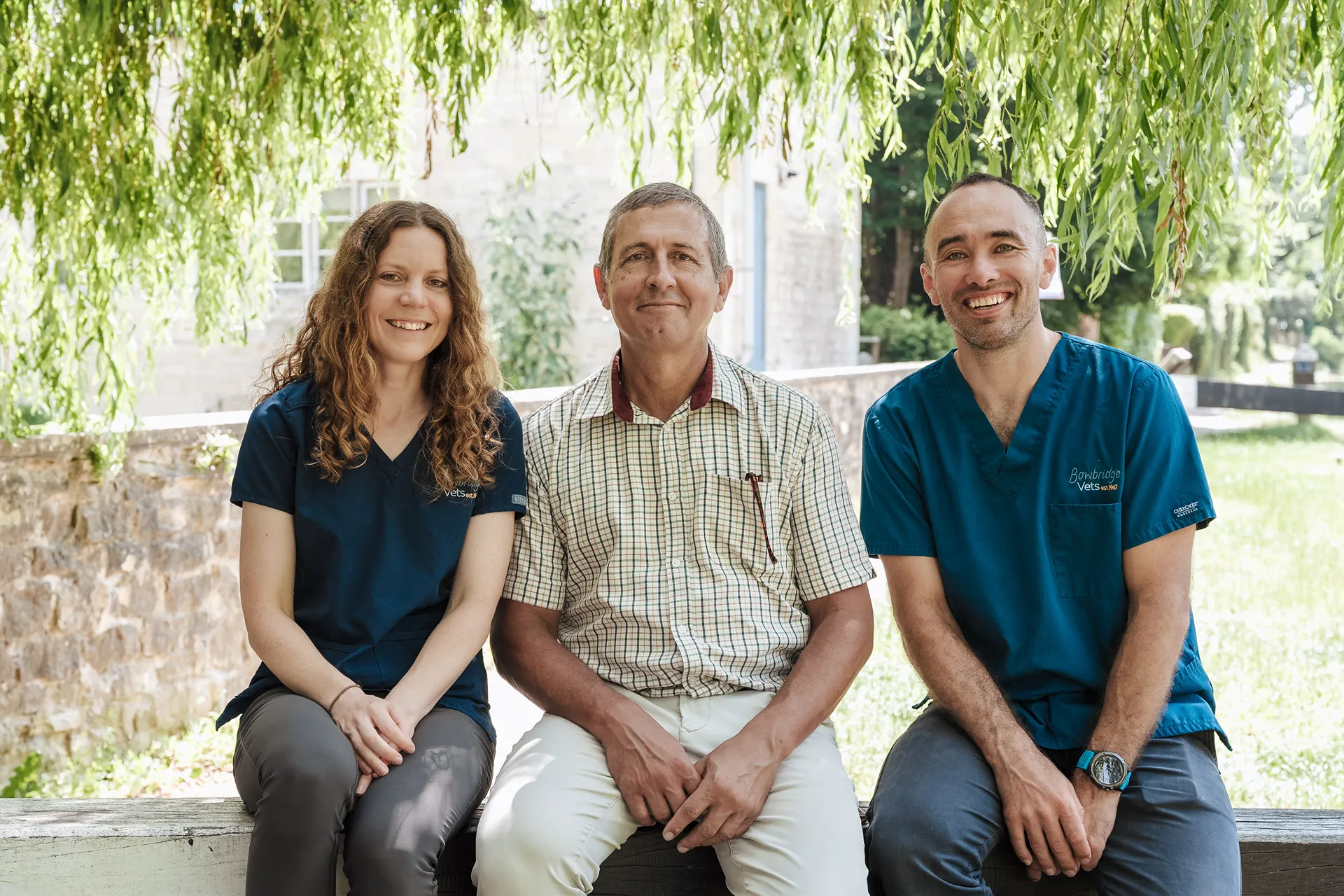 The owners of Bowbridge Vets sitting on a stone wall