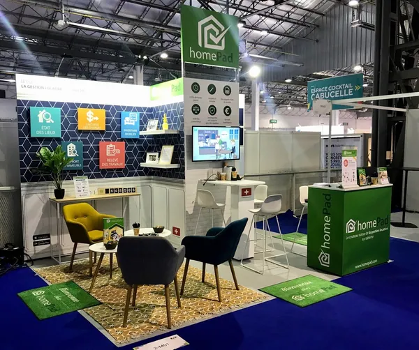 Modular exhibition stand with lounge seating, shelving and screen