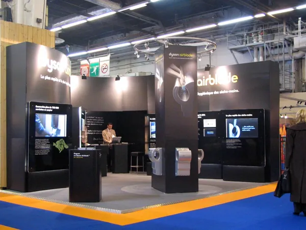 Black custom exhibition stand with product demonstration pods and screens