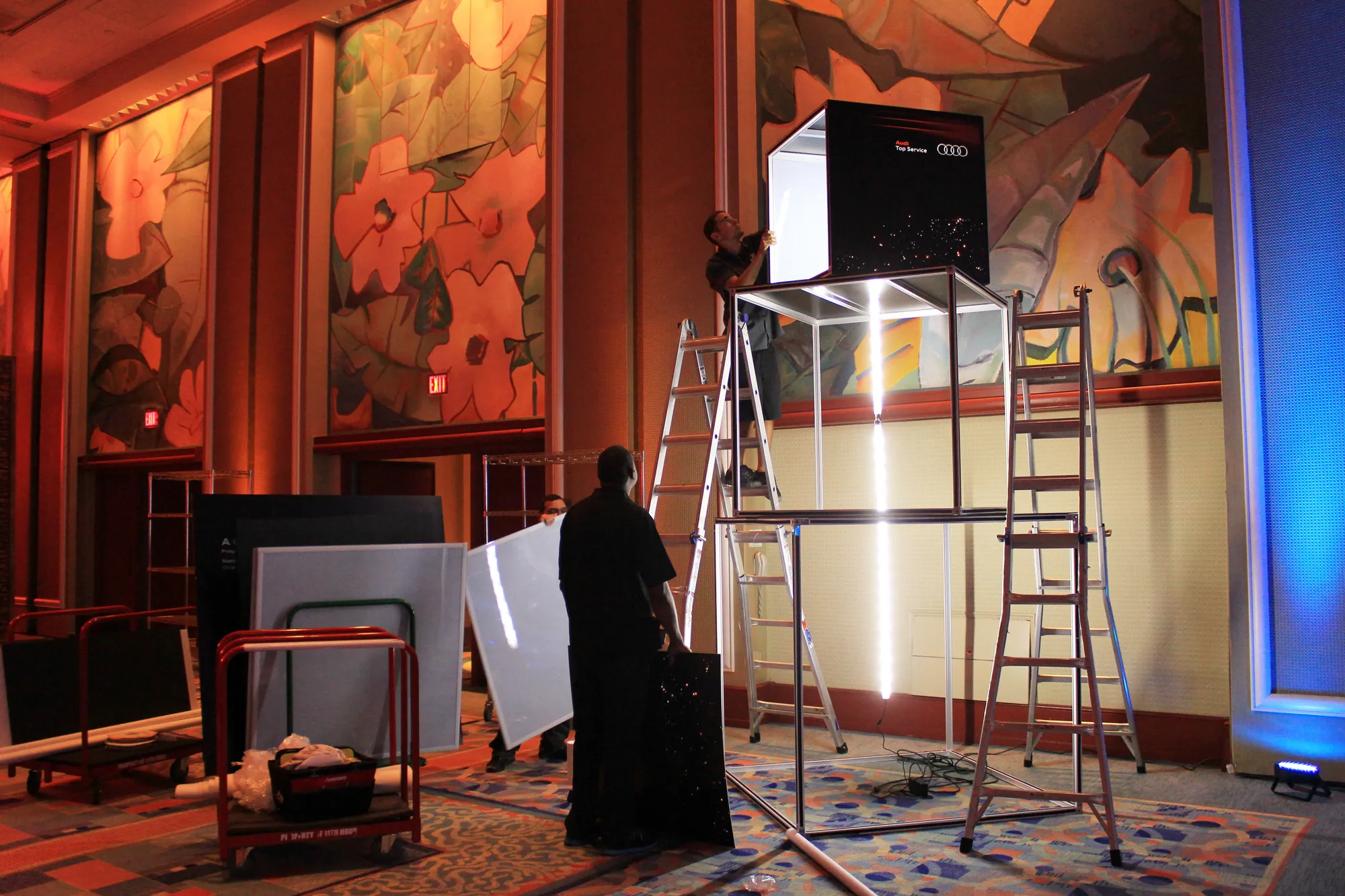 Installer building an illuminated T3 cube display in a venue