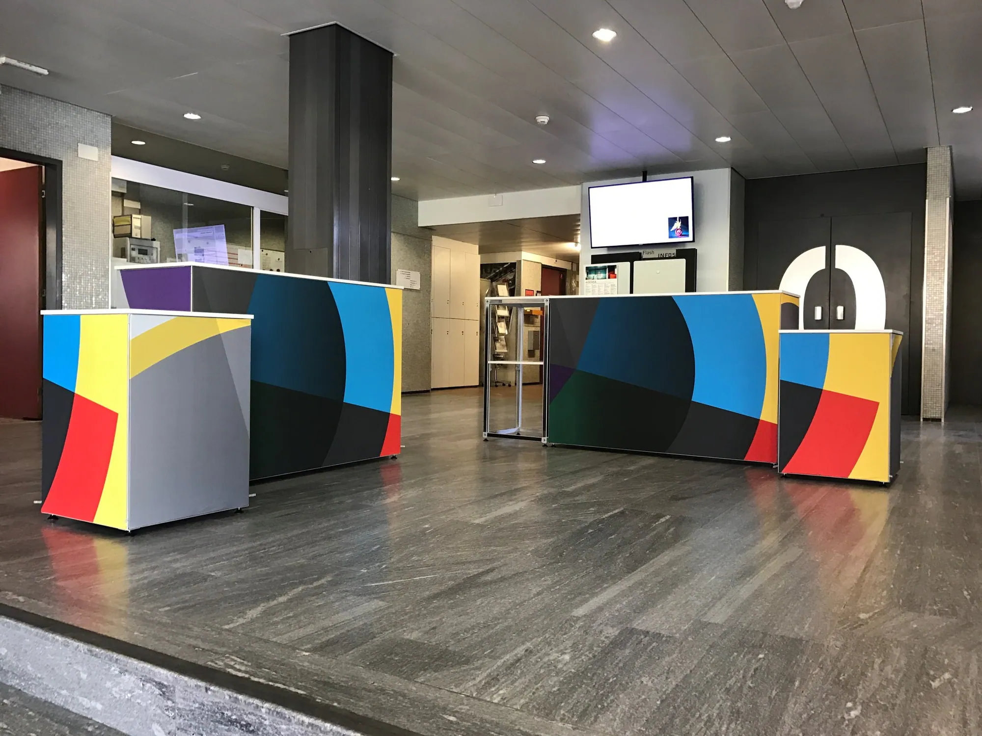 Graphic-wrapped reception counters built with T3 in a venue foyer