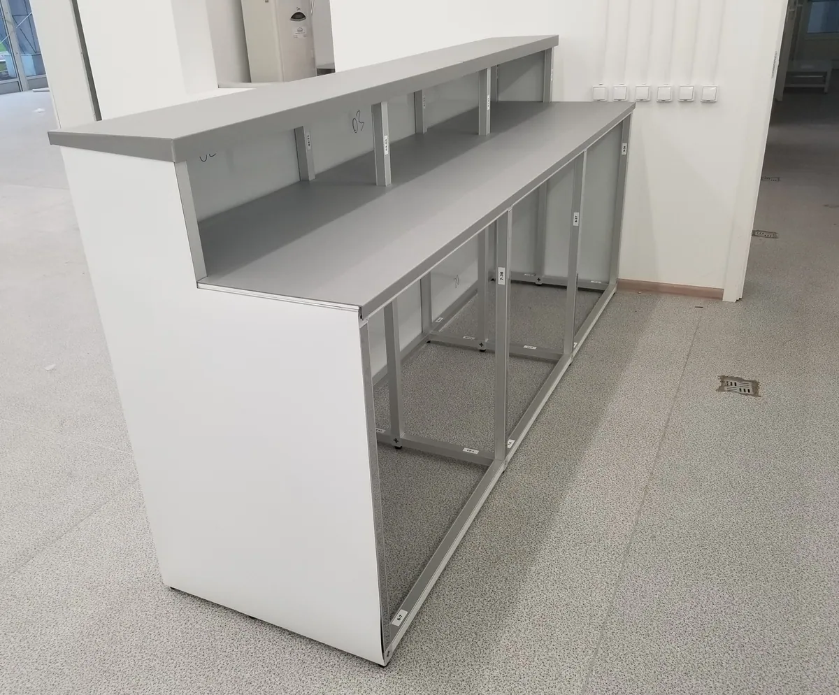 White T3 reception counter with open aluminium frame shelving