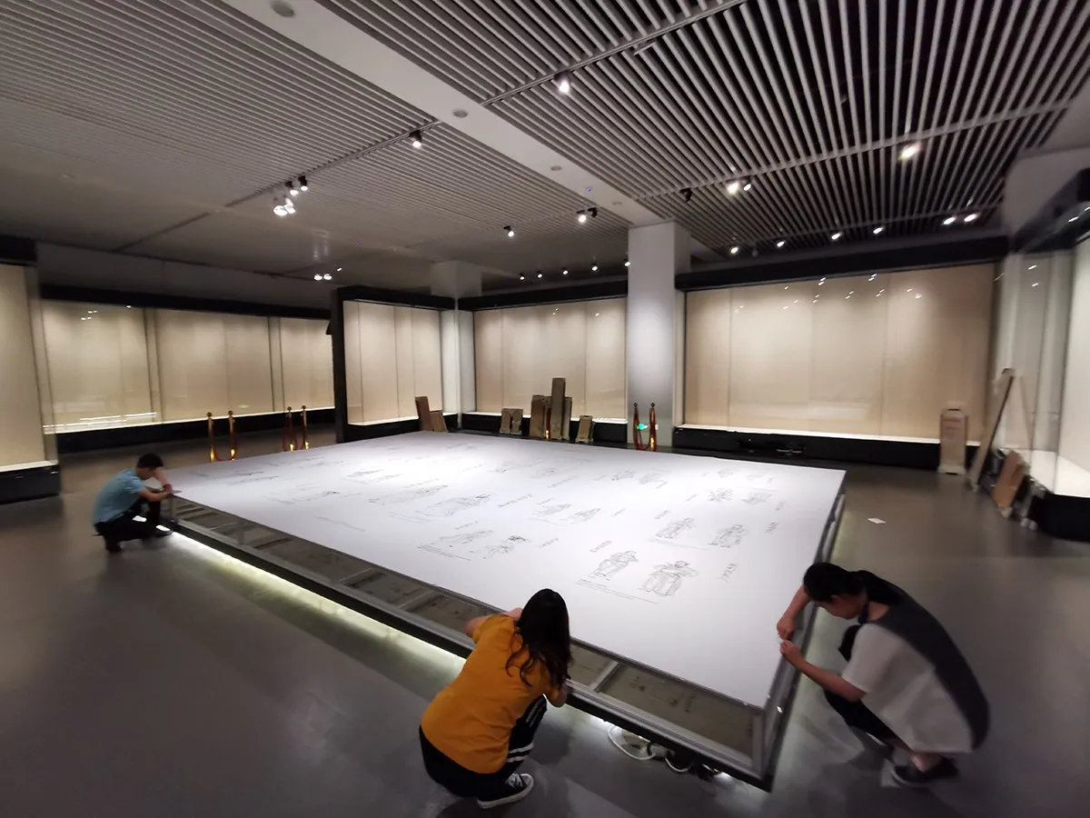 Installers fitting a large illuminated T3 plinth in a museum gallery