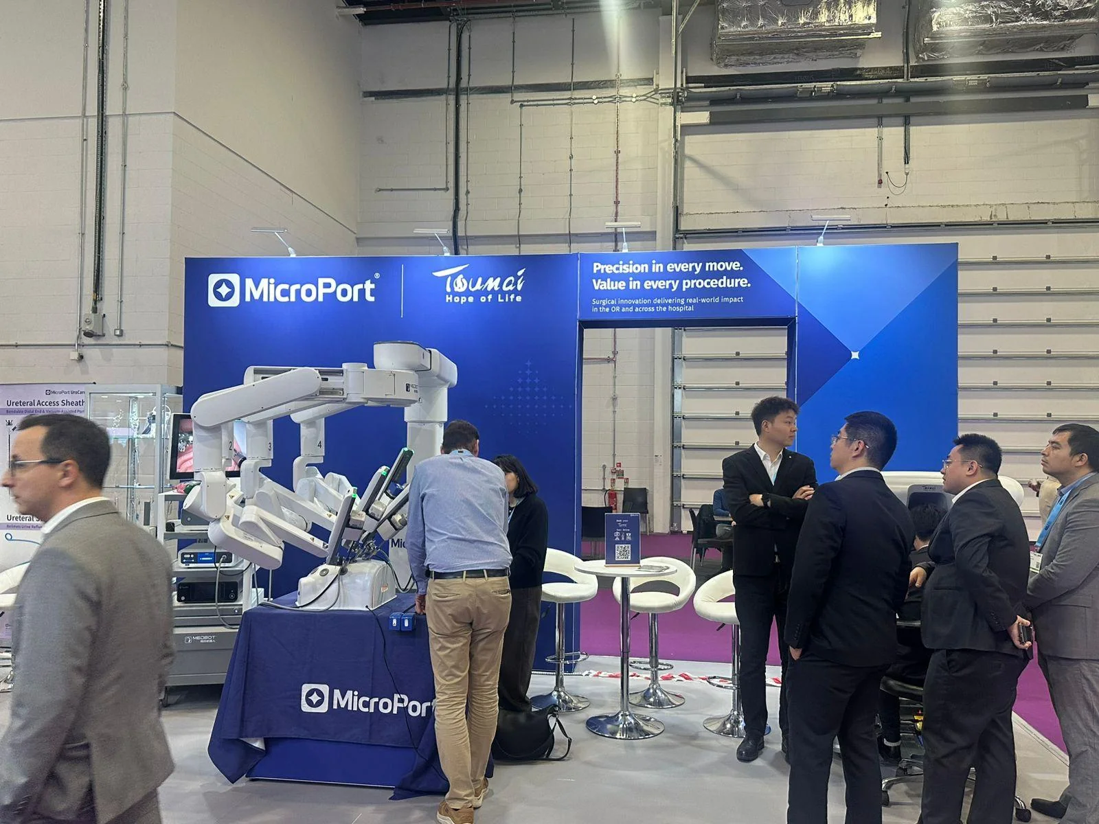 MicroPort exhibition stand at EAU 2026, ExCeL: visitors gathered around the robotic demonstration system on the blue stand