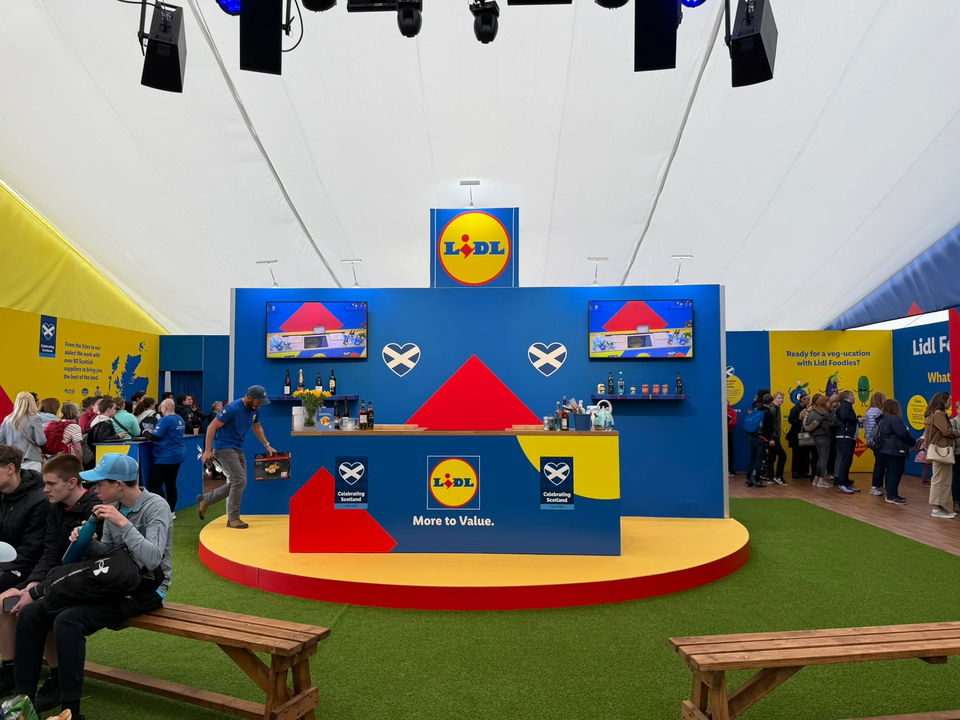 Lidl stand at RHS 2026: stage with a red circular platform, blue backdrop and green turf in a marquee