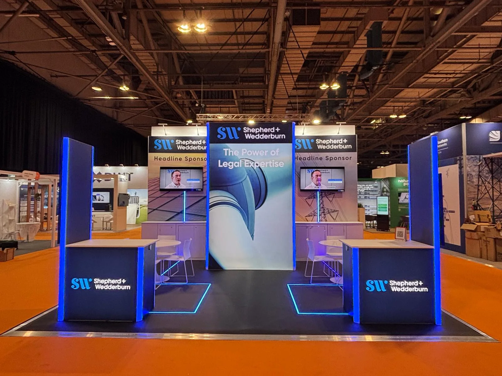 Shepherd & Wedderburn stand at All Energy 2026: stand with a blue-lit counter, wave-shaped graphic panel and two screens