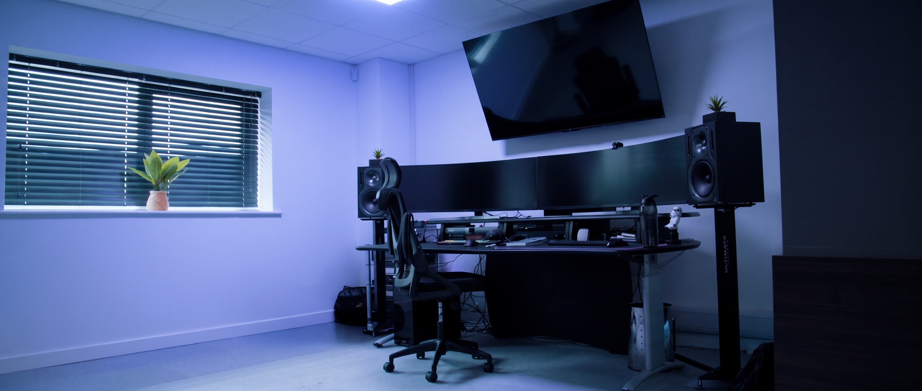 a desk with a chair and a large television on the wall