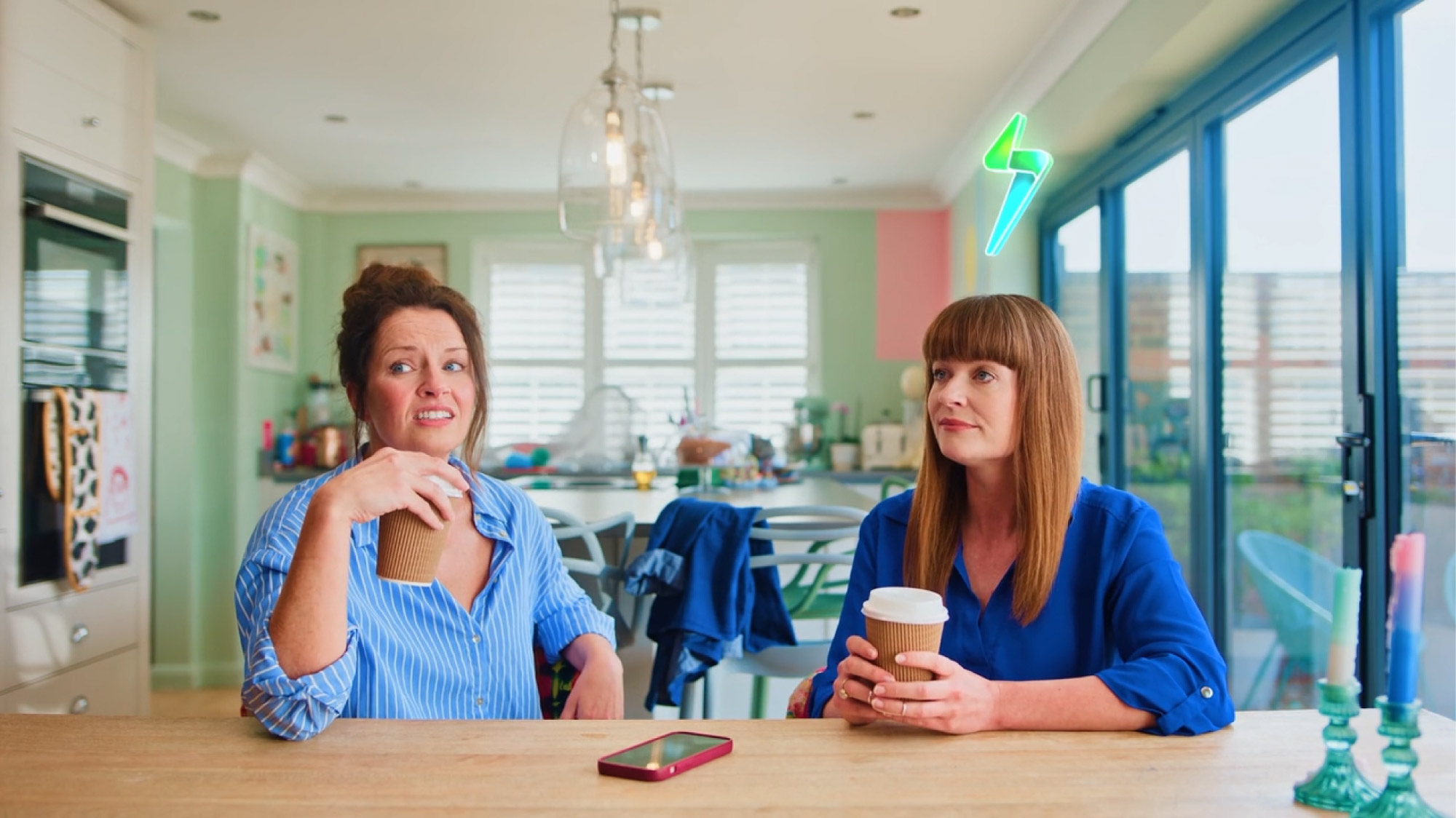 two women sitting at a table with coffee cups