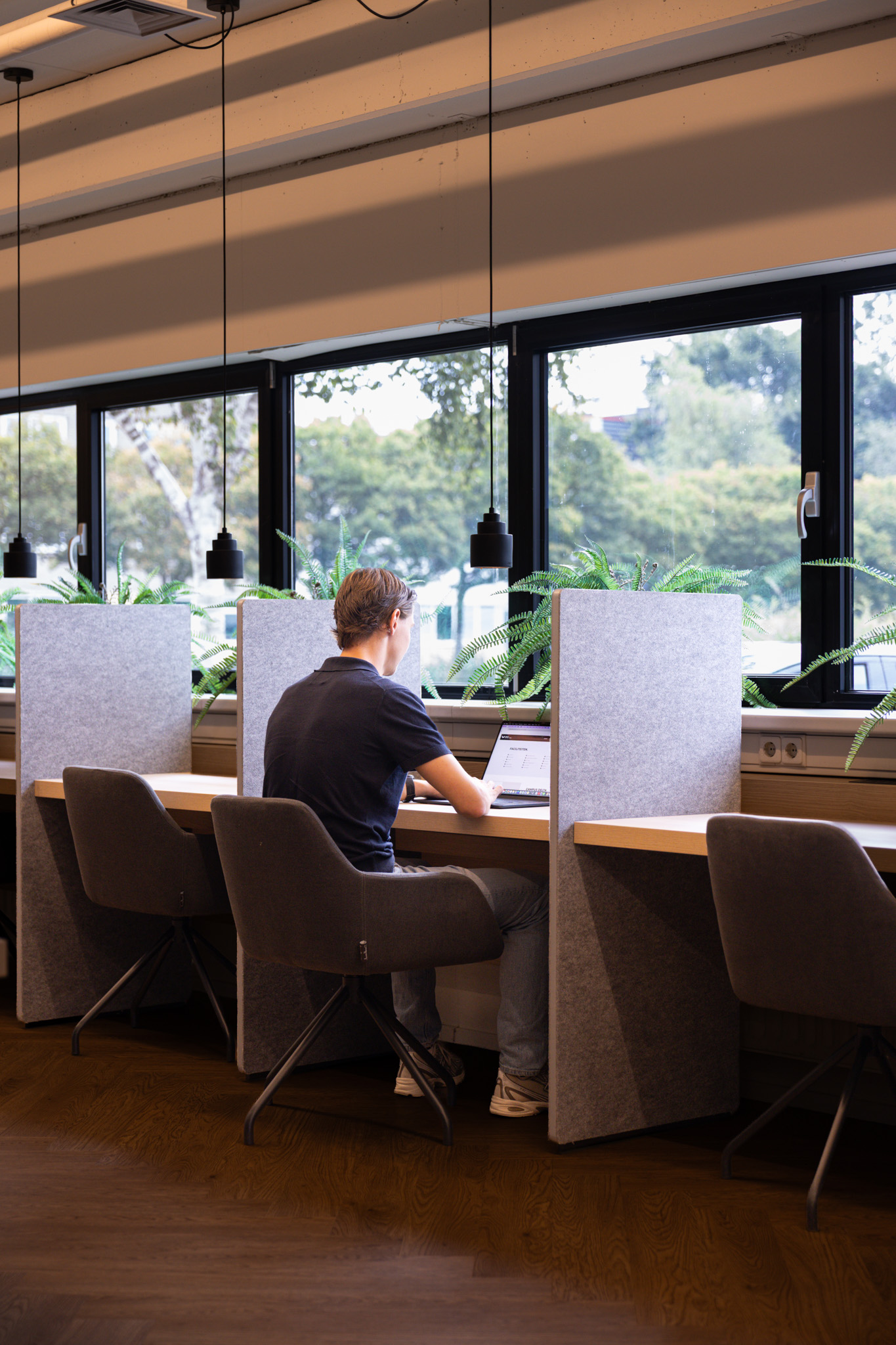 Persoon aan het werk bij het raam in Campus Delta