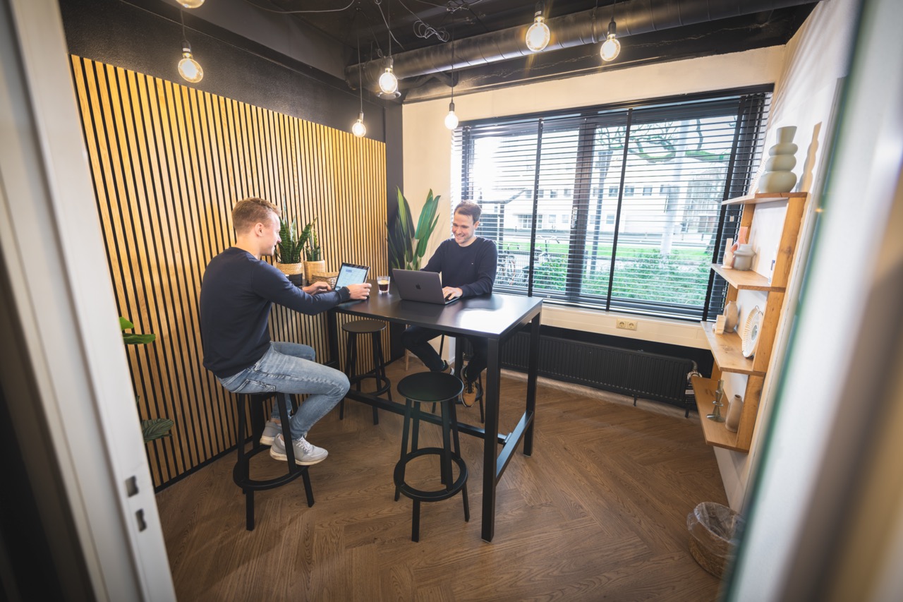 Vergaderruimte met een hoge tafel en twee mensen overleggen bij Campus Dreesz