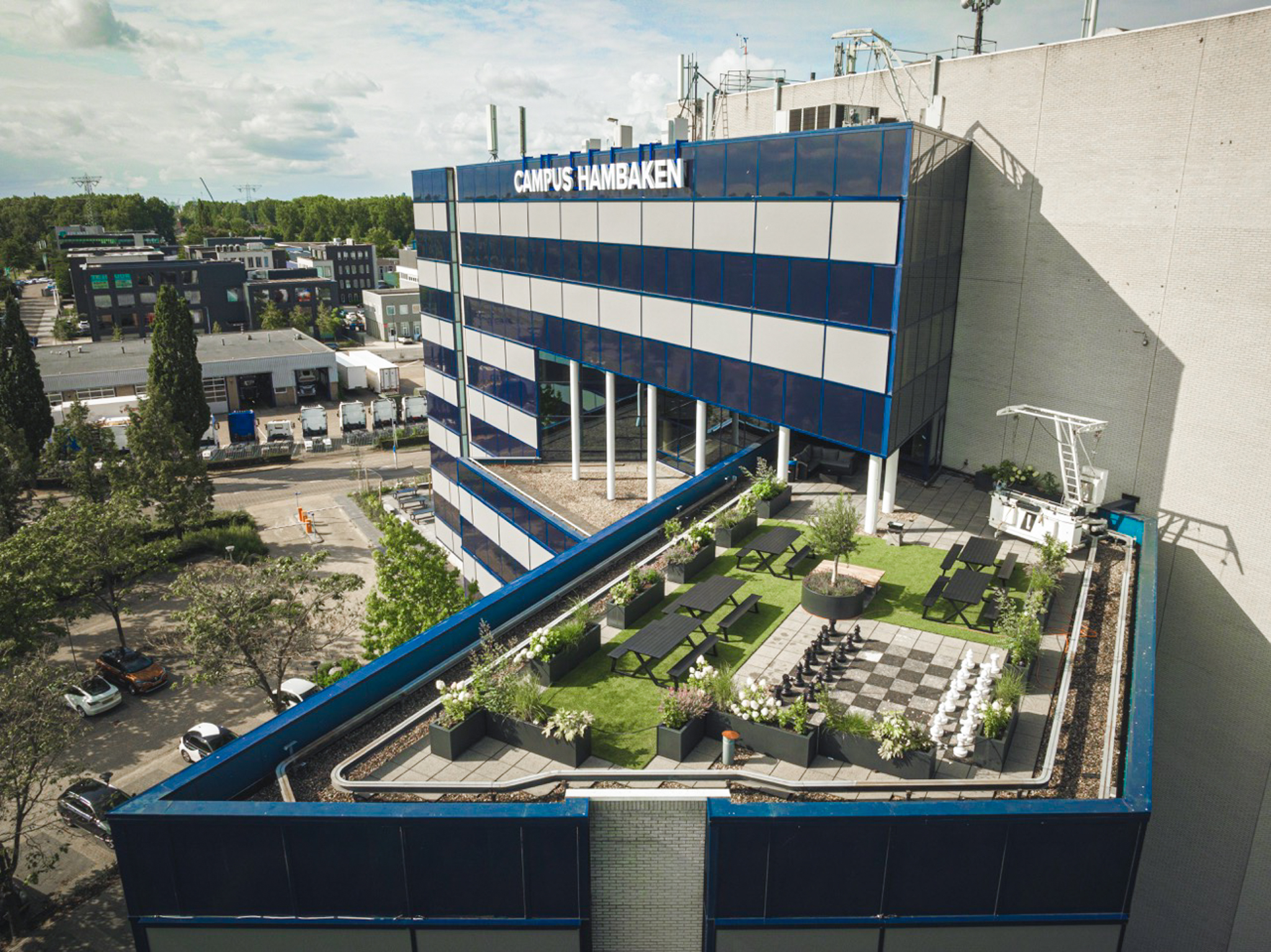 Dakterras van Campus Hambaken in Den Bosch met zitplekken, groen en een groot schaakbord.