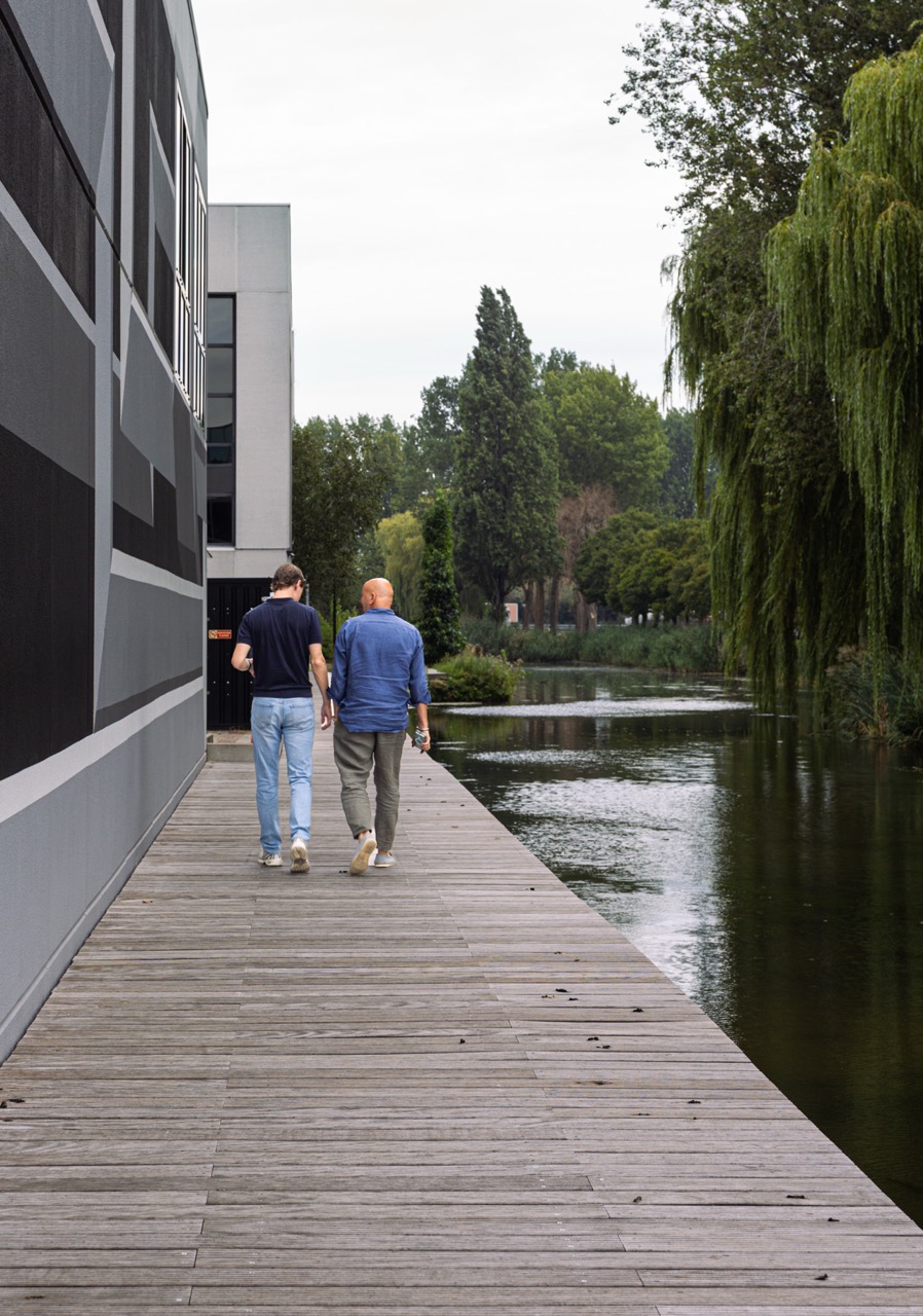 Twee mensen wandelen over de vlonder langs het water bij Campus Delta in Capelle aan den IJssel.