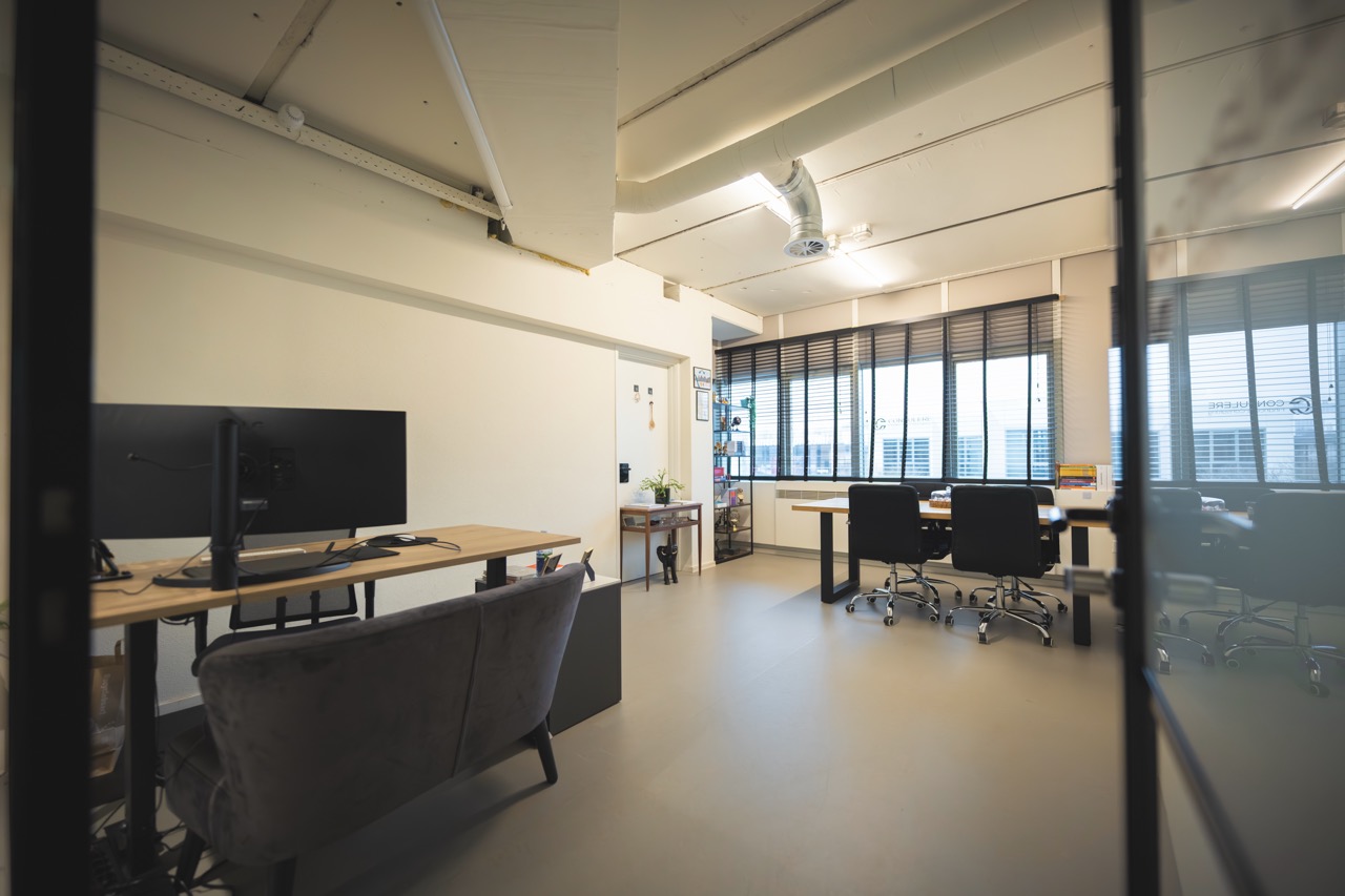 Kantoorruimte met bureaus, beeldschermen en een zitbank bij Campus Delta.