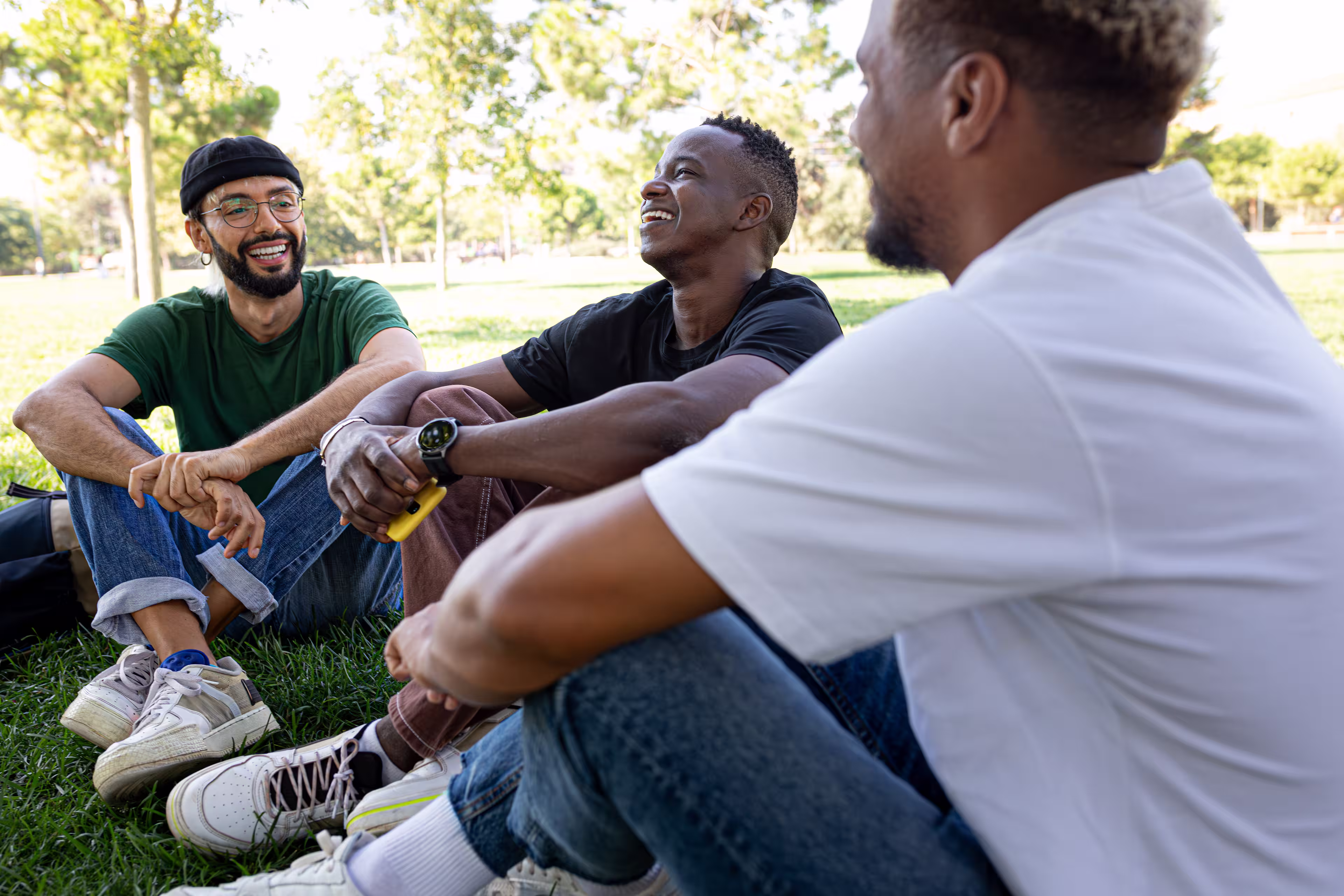 Young men friends laughing in grassy park