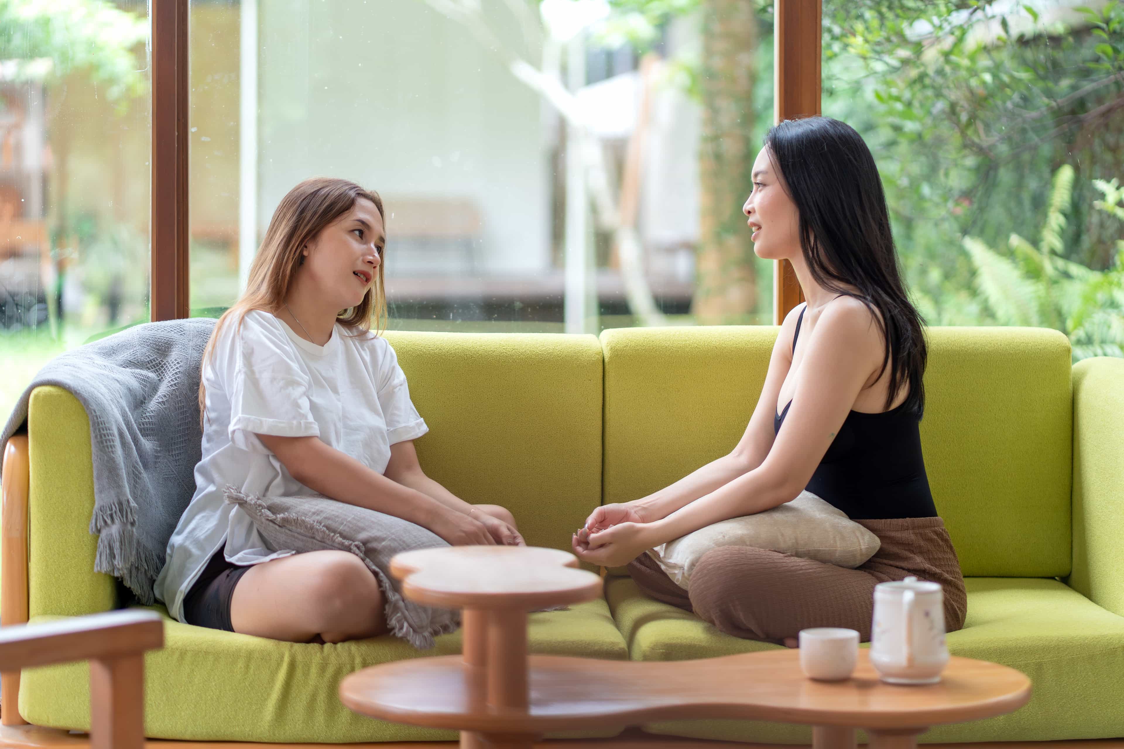 Woman listens compassionately to her friend on olive green couch