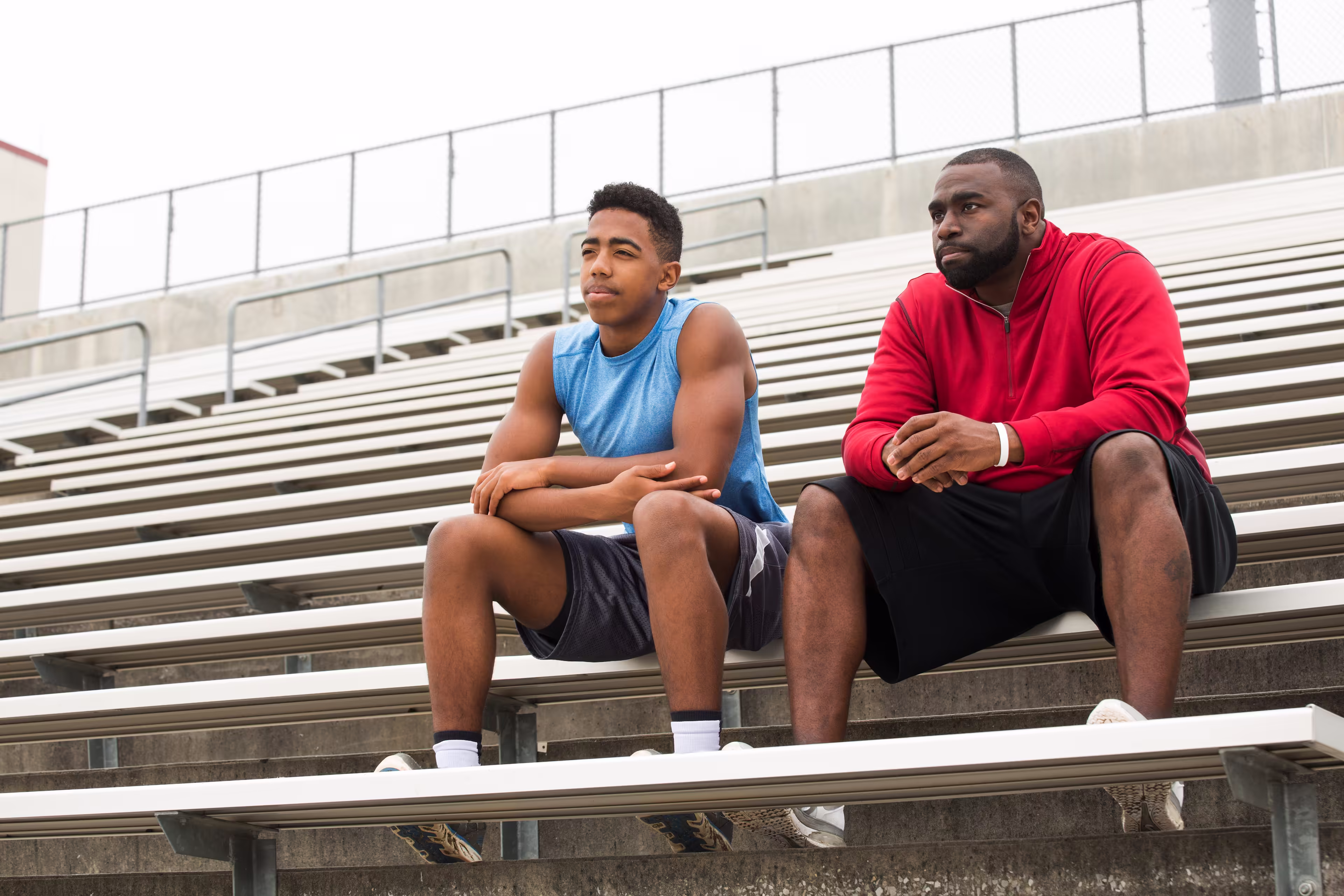 Father or coach sitting contemplatively with student-athlete