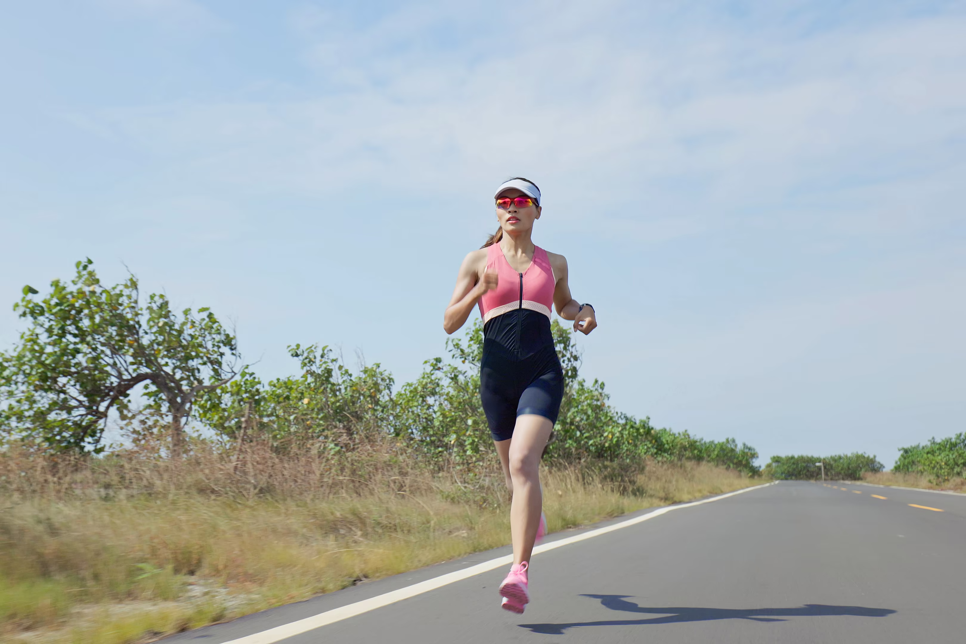 Elite adult woman athlete training on empty rural road for long distance race