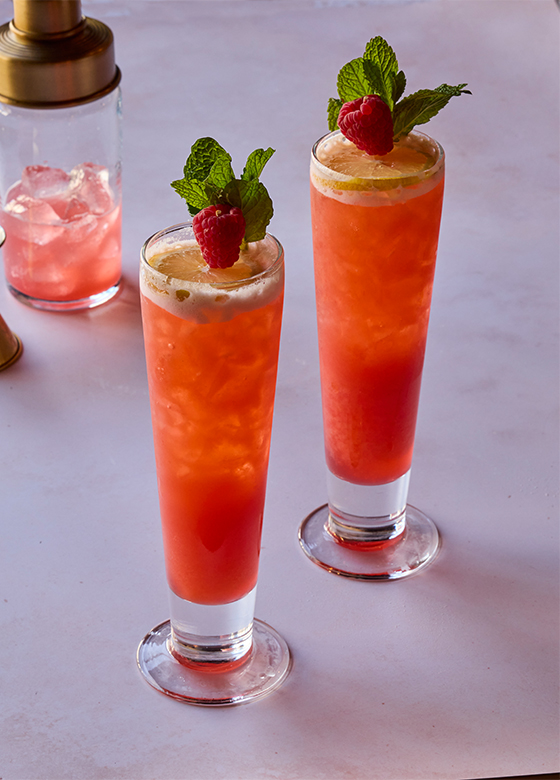 Two handcrafted raspberry cocktails garnished with fresh raspberries and mint, served at Saint & Second .