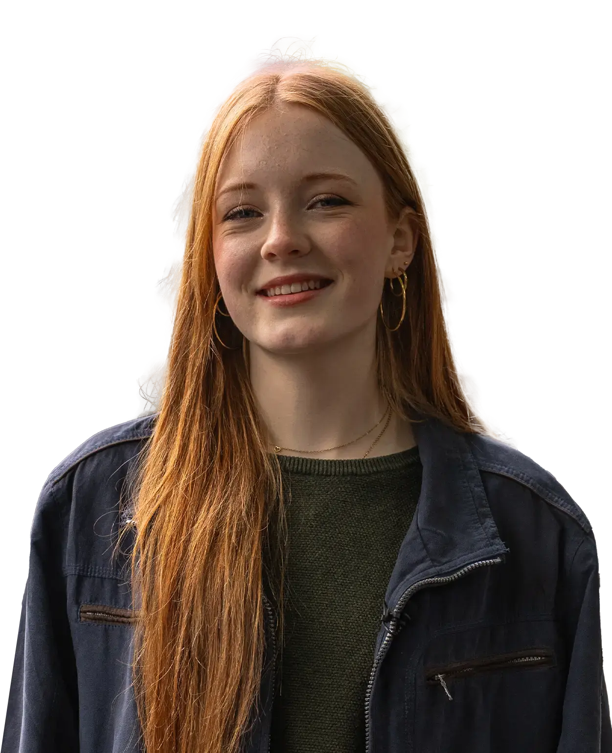 Jonge vrouw met lang rood haar, goudkleurige oorbellen en een donkerblauwe jas, glimlachend.