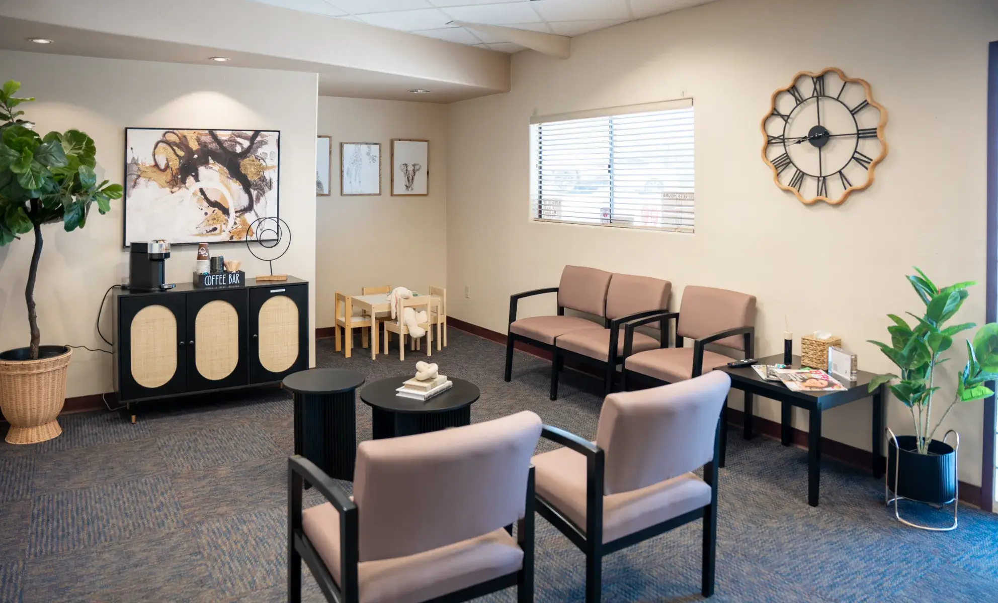 Small waiting room with four chairs, a coffee station, and a wall clock.