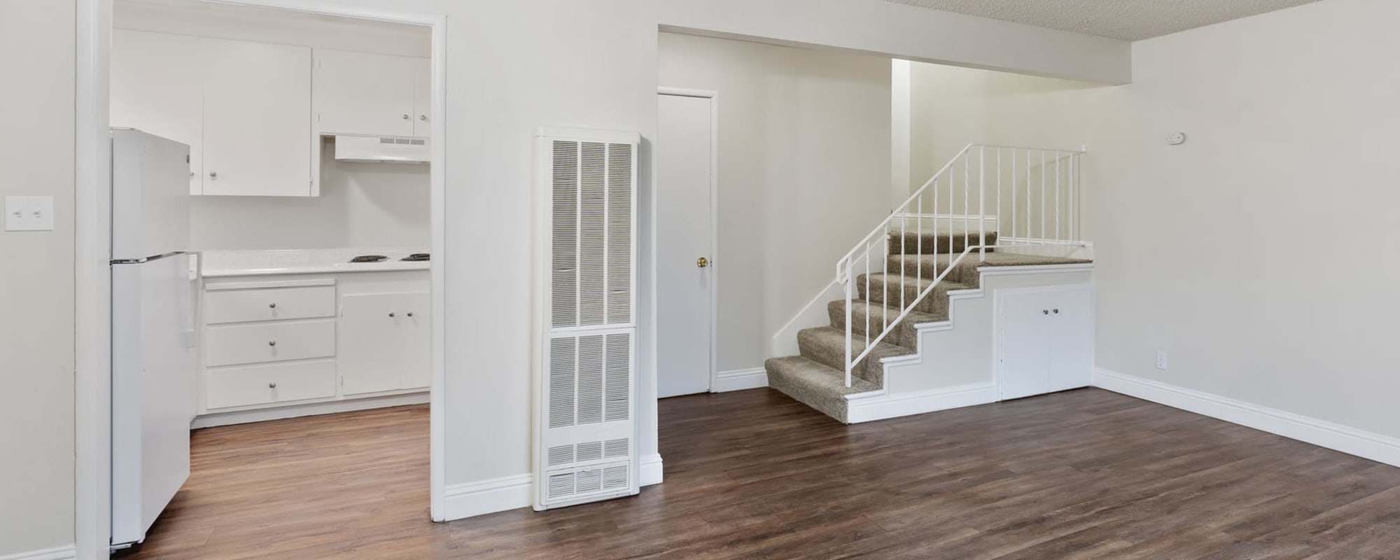 Unfurnished living area with view of stairs and kitchen