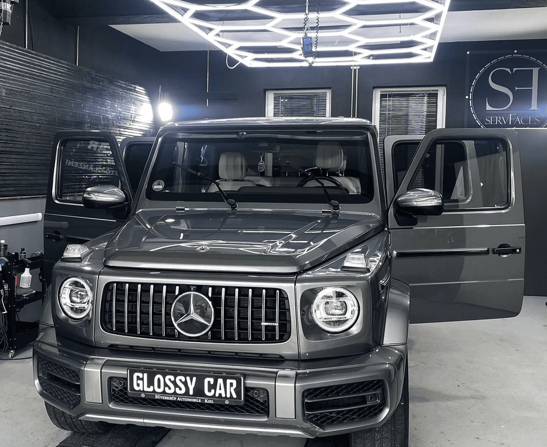 Graues Mercedes G-Klasse Luxusfahrzeug in moderner von Garage von Glanzwerk Autoservice mit offenen Vordertüren.