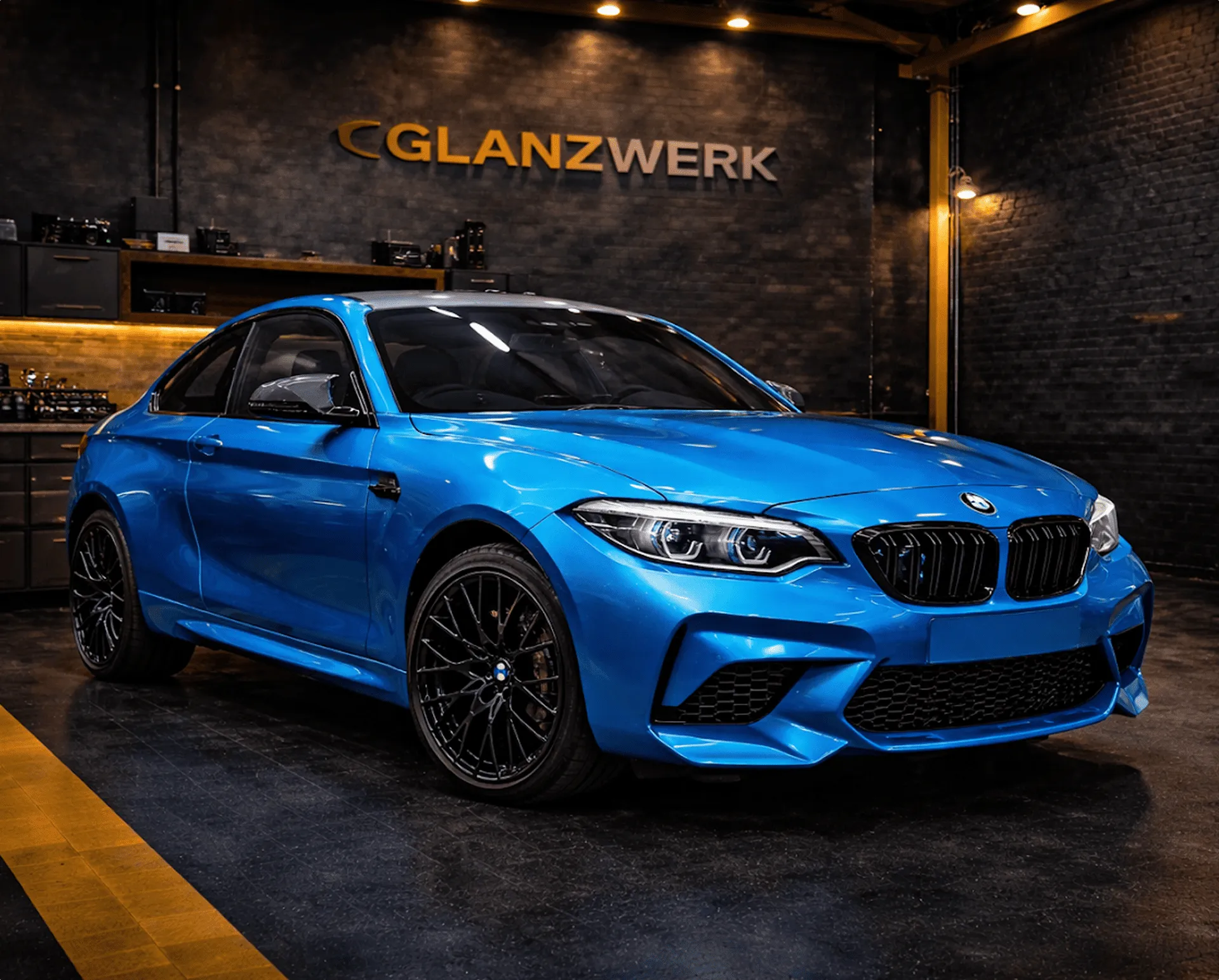 Blauer BMW-Sportwagen in der Werkstatt von Glanzwerk Autoservice mit dunklen Wänden.
