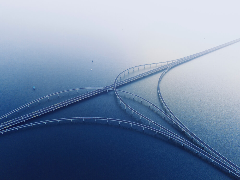 Aerial view of a highway bridge interchange branching across water in a misty setting.