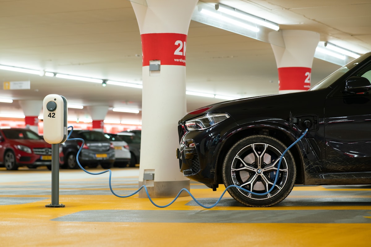 Black BMW electric vehicle charging at a numbered charging station in a parking garage