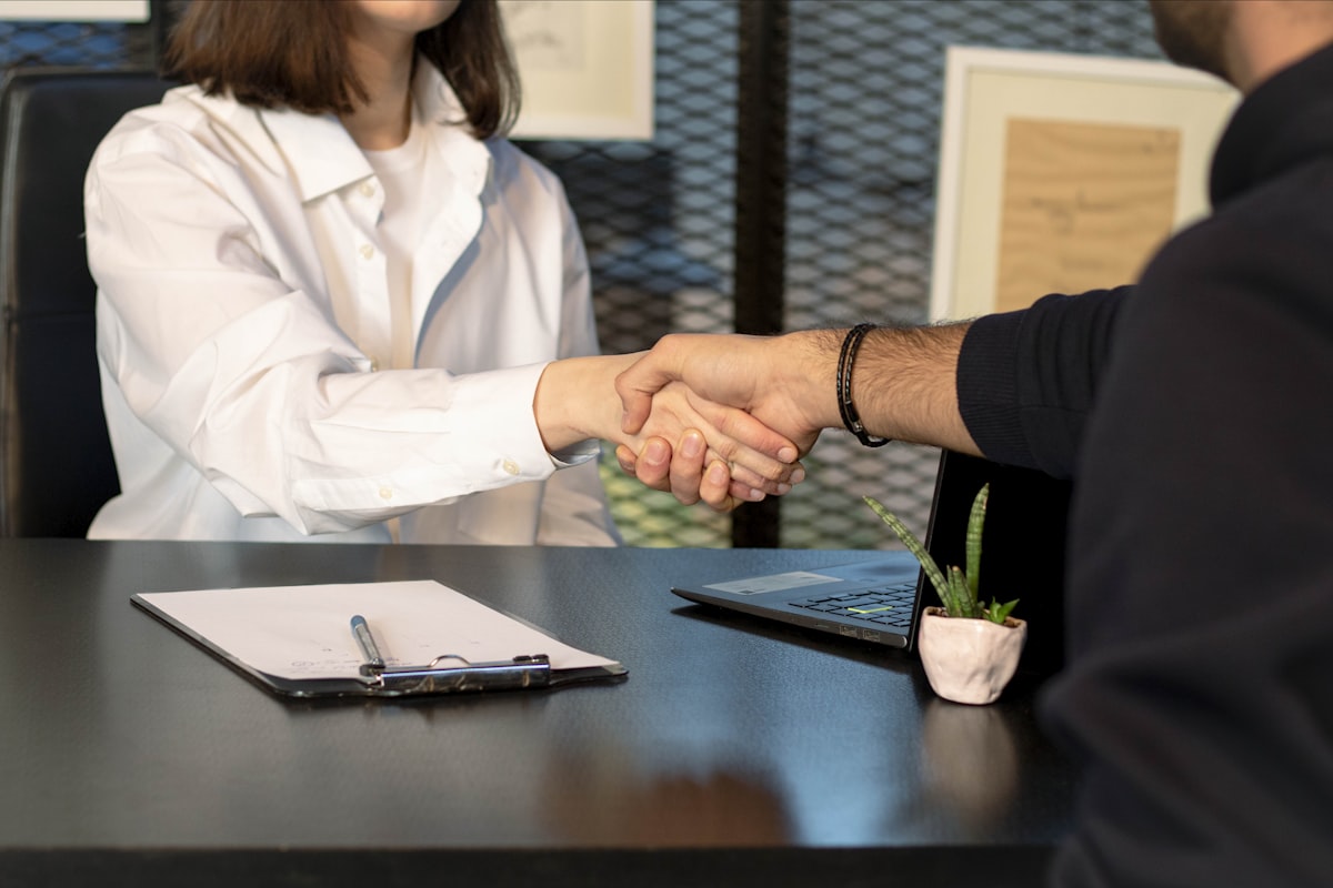Business professionals shaking hands across a desk to close a deal