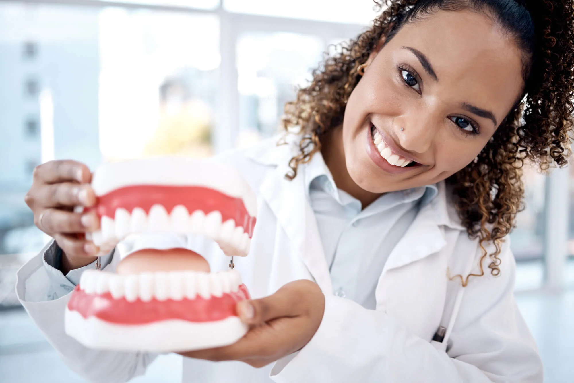 Smiling dentist holding dental model Zoom whitening for teeth