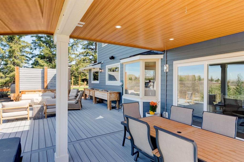 Covered rear deck with cedar-finished ceiling, dining table, and lounge area