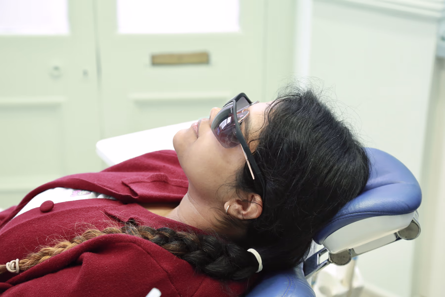 Woman with braid lying back in a chair wearing glasses in a bright room.