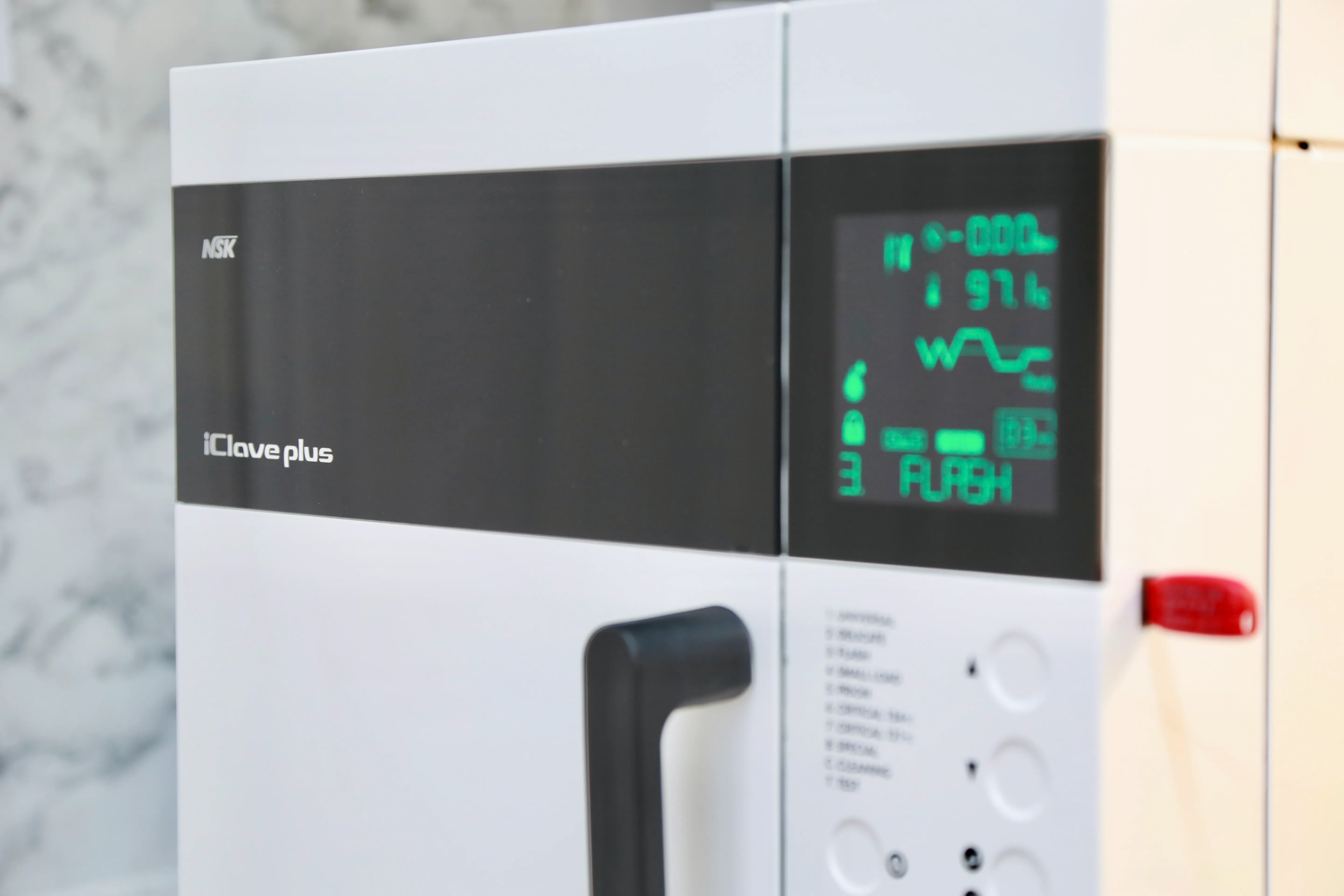 Close-up of NSK iClave Plus sterilizer control panel showing digital display and buttons.