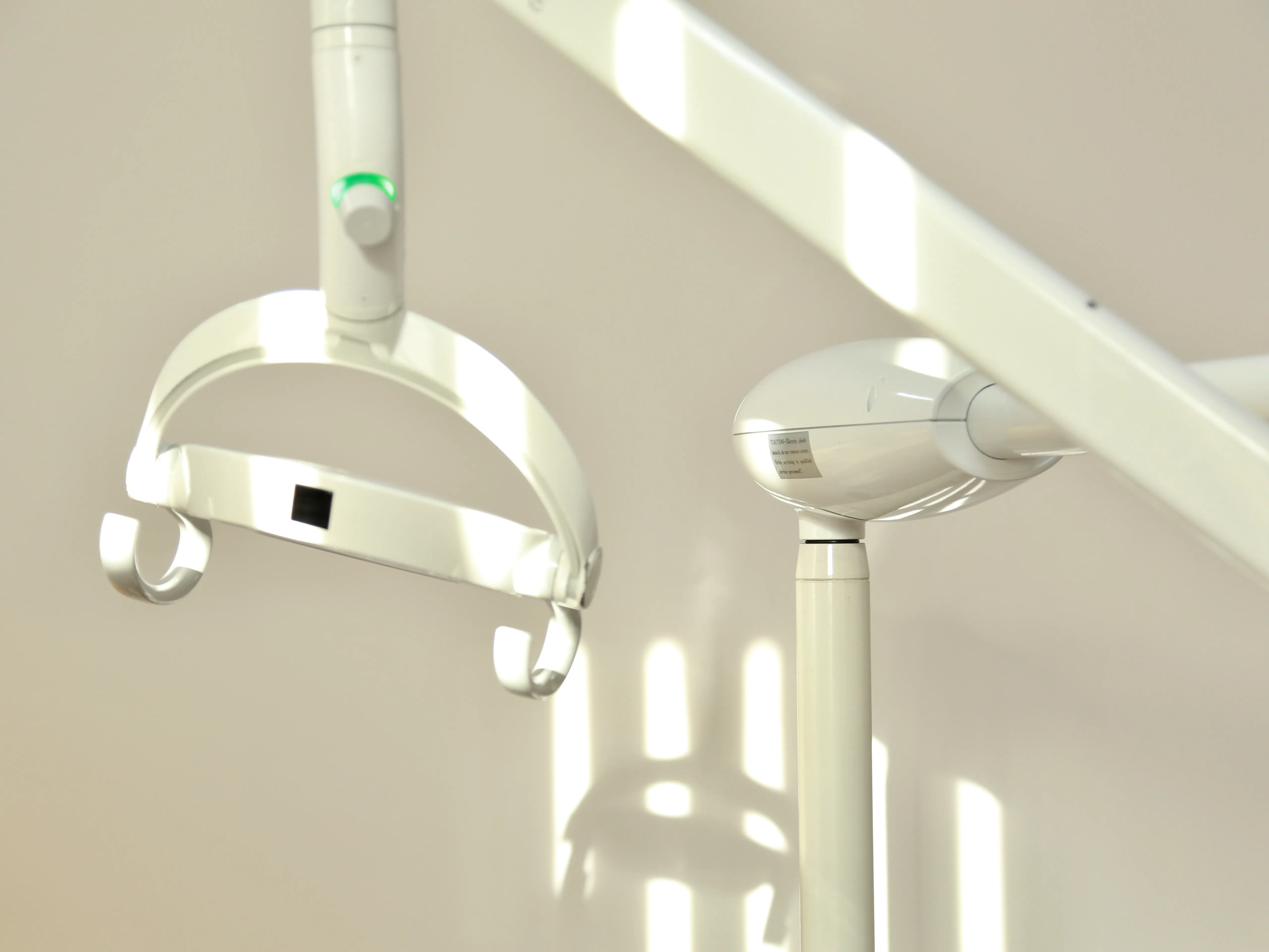 Close-up of a white dental examination light and a dental suction tool in a clinic.